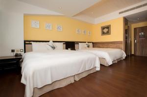 two beds in a hotel room with white sheets at Hotelday+ Kenting in Kenting