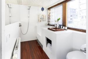 a white bathroom with a shower and a sink at Stunning boat with a view in Amsterdam