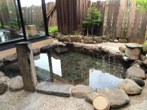 a pool in a backyard with a fence and a pond at Dormy Inn Akita in Akita