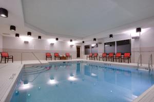uma grande piscina com cadeiras e mesas vermelhas em Holiday Inn Express & Suites Ottawa East-Orleans, an IHG Hotel em Ottawa