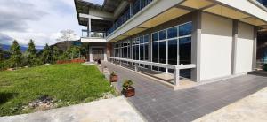 a large house with a patio and a yard at Leely Garden Valley Lodge Tambunan in Tambunan