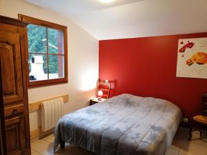 a bedroom with a bed and a red wall at Chalet au bord du lac de Longemer in Xonrupt-Longemer