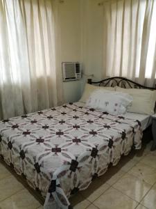 een bed met een dekbed in een slaapkamer bij Cranberry's Place-near CONVENTION center in Iloilo City