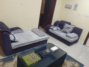 een woonkamer met 2 stoelen en een bank bij فندق الجوهرة in Al Buraymī