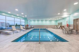 una piscina en el vestíbulo del hotel con sillas y mesas en Holiday Inn Express & Suites Moncton, an IHG Hotel en Moncton