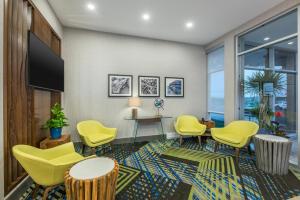 a waiting room with yellow chairs and a flat screen tv at Holiday Inn Express & Suites Moncton, an IHG Hotel in Moncton