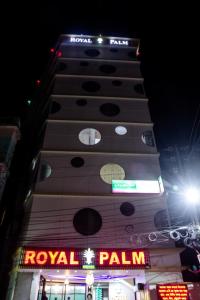 un edificio alto con una señal real de palco por la noche en Royal Palm Hotel, en Sylhet