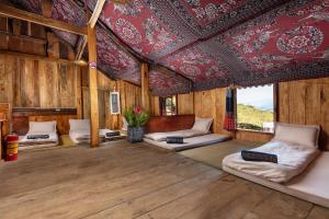 a room with several beds in a room with a ceiling at Hmong Sister House and Trekking in Sa Pa