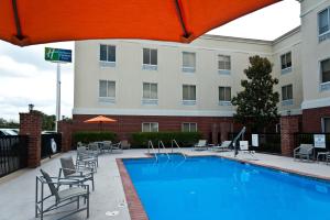 a pool at a hotel with chairs and a building at Holiday Inn Express Hotel & Suites Scott-Lafayette West, an IHG Hotel in Scott