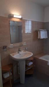 a bathroom with a sink and a tub and a mirror at Hôtel du Port Bar Restaurant in Sarzeau