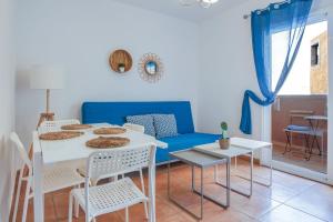 ein Wohnzimmer mit einem blauen Sofa und einem Tisch und Stühlen in der Unterkunft Center Holiday Corralejo in Corralejo