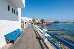 eine Reihe blauer Bänke auf einem Pier neben dem Wasser in der Unterkunft Center Holiday Corralejo in Corralejo