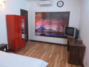 a bedroom with a television and a painting on the wall at KH&Aacute;CH SẠN HƯƠNG SEN PH&Uacute; Y&Ecirc;N in Tuy Hoa