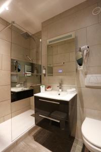 a bathroom with a sink and a toilet and a mirror at Hotel Montbrillant in Geneva