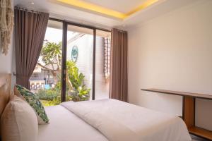 a bedroom with a bed and a large window at The Palms Canggu in Canggu