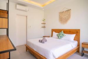 a bedroom with a white bed and a television at The Palms Canggu in Canggu