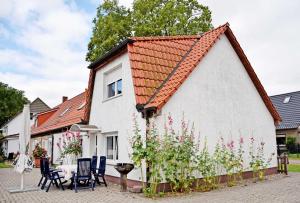 une maison blanche avec un toit rouge, des chaises et des fleurs dans l'établissement Ferienwohnungen auf dem Pommernhof, à Samtens