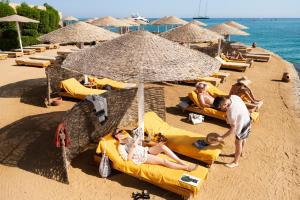 eine Gruppe von Menschen, die unter einem Sonnenschirm am Strand liegen in der Unterkunft Three Corners Ocean View El Gouna - Adults Only in Hurghada