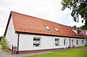 une maison blanche avec un toit orange dans l'établissement Ferienwohnungen auf dem Pommernhof, à Samtens