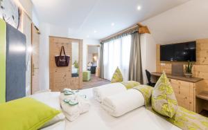 a bedroom with a large white bed and a television at Natur & Aktiv Hotel Rogen in Mühlbach