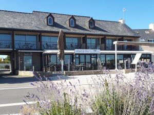 a building with a umbrella and tables and chairs at Hôtel du Port Bar Restaurant in Sarzeau