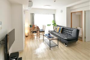 Jpride Uemachidai Condo في أوساكا: غرفة معيشة مع أريكة جلدية سوداء وطاولة