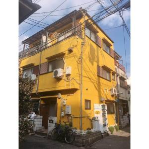 een geel gebouw met een fiets voor het gebouw bij 林林の民宿-関空直達,通天閣近い, 3階建て一軒家 in Osaka