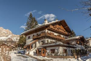 une maison dans la neige avec une montagne en arrière-plan dans l'établissement Cantore, Cortina by Short Holidays, à Cortina dʼAmpezzo