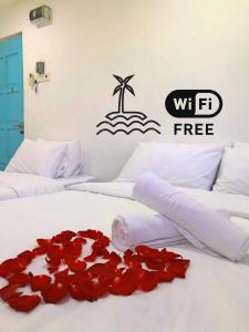 um quarto com duas camas com rosas vermelhas na cama em IBAI BEACH GUESTHOUSE em Kuala Terengganu