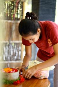 a woman standing at a table cutting a cake at Vinayaka Ubud in Ubud