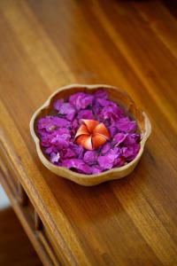 uma tigela de flores roxas com uma borboleta. em Vinayaka Ubud em Ubud