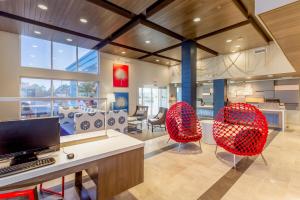 a living room with two red chairs and a desk at Holiday Inn Express Orange Beach - On The Beach, an IHG Hotel in Orange Beach