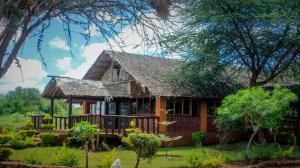 a wooden house with a thatched roof at Teen Ranch Kenya in Amboseli