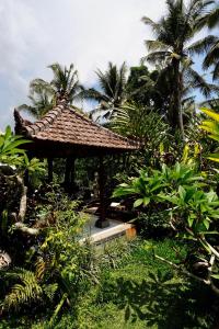 eine kleine Hütte in einem Garten mit Palmen in der Unterkunft Vinayaka Ubud in Ubud