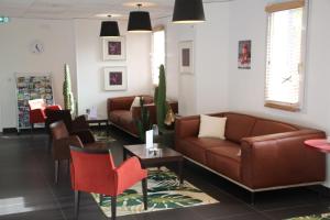 een wachtkamer met een leren bank en stoelen bij Kyriad Quimper Sud in Quimper