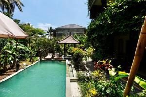 a swimming pool in front of a house at Vinayaka Ubud in Ubud