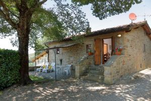 a stone cottage with a tree and a patio at Podere I Sorbi in San Donato in Fronzano