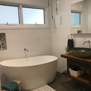 a bathroom with a large tub and a sink at Sawtell Beach Shack 1 in Sawtell