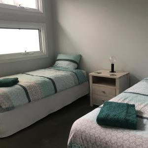 a bedroom with two beds and a window at Sawtell Beach Shack 1 in Sawtell