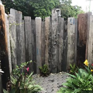 a wooden fence with a shower in a garden at Sawtell Beach Shack 1 in Sawtell