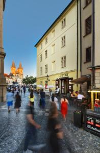 a group of people walking down a street with buildings at Hotel Lippert in Prague