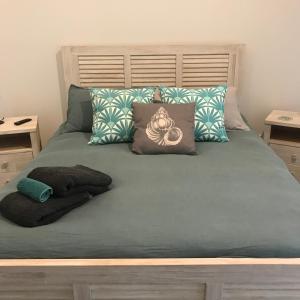 a bed with green sheets and pillows in a bedroom at Sawtell Beach Shack 1 in Sawtell