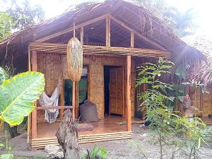 a wooden house with a porch in a forest at Herbs Guest House and Restaurant near the Sea in Moalboal