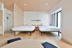 two beds in a room with white furniture at REF Kumamoto by VESSEL HOTELS in Kumamoto