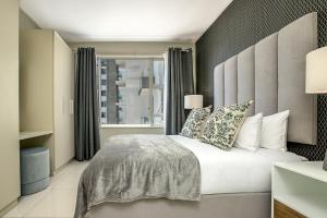 Un dormitorio con una cama grande y una ventana en The Tyrwhitt Rosebank Apartments, en Johannesburgo
