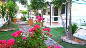 un giardino con fiori rosa e palme e una casa di Residence "Il Faro" a Isola Capo Rizzuto