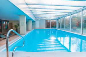 an indoor swimming pool with blue water and windows at Fletcher Resort-Hotel Zutphen in Zutphen
