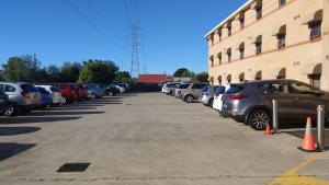 ein Parkplatz mit Autos neben einem Gebäude in der Unterkunft Arena Hotel (formerly Sleep Express Motel) in Sydney