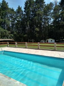 une piscine bleue avec une clôture et des arbres dans l'établissement Sítio Colibri - Serra da Mantiqueira, à Brazópolis