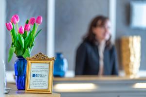 a woman sitting at a table with a vase of flowers at Hotel Ambasciatori in Brescia